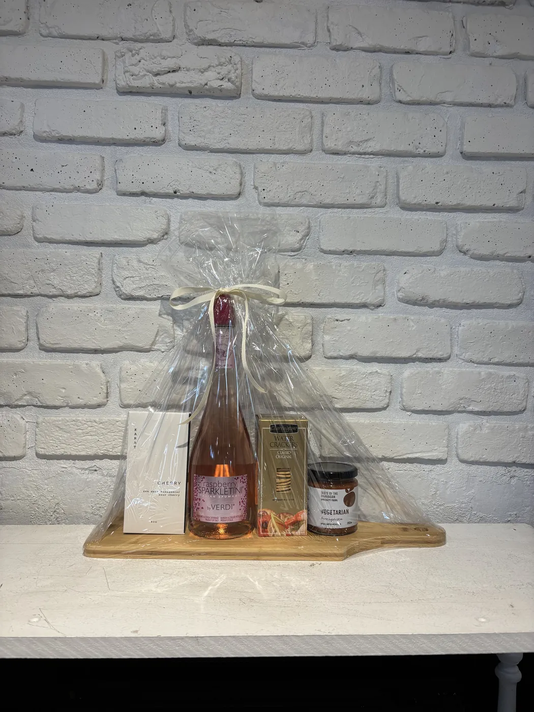 Raspberry Sparkletini gift set with antipasto, water crackers and cherry chocolate on a wooden board