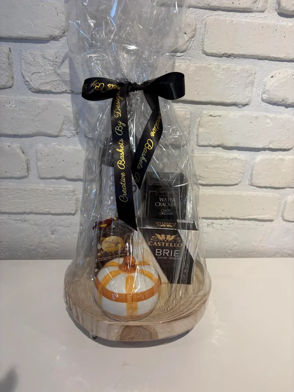 Decorative wood pedestal gift set with red wine, brie, water crackers, local chocolates and a fall pumpkin