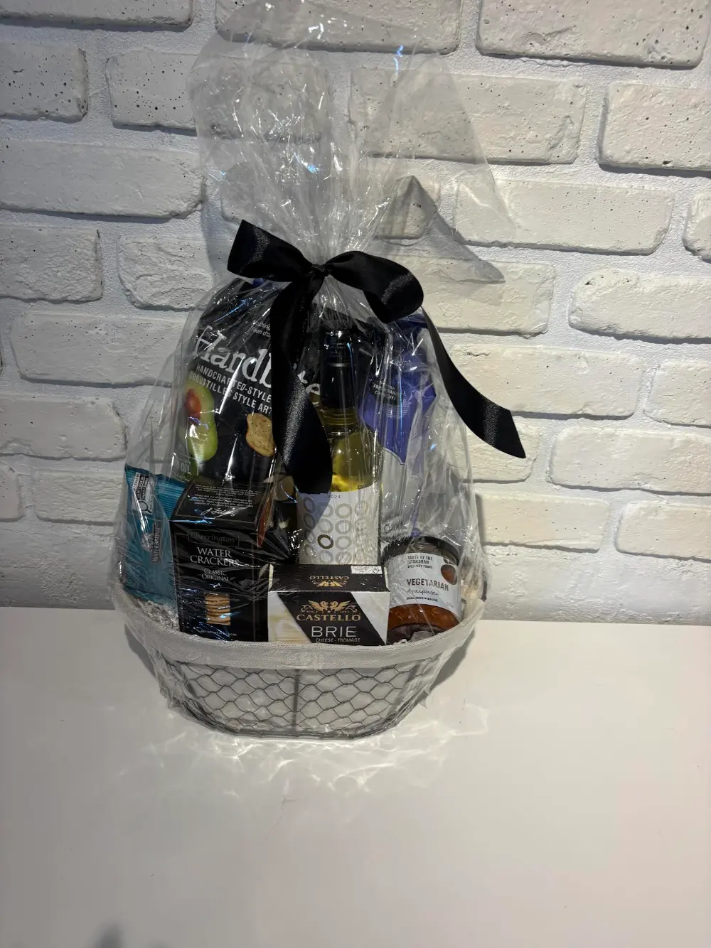 White wire basket gift set with white wine, Castello brie, Hardbite chips, water crackers and local vegetarian antipasto
