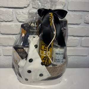 Welcome Gift Basket with Latitude 50 white wine, Castello brie, a black polka dot kitchen towel and mint citrus hand soap in a wicker basket